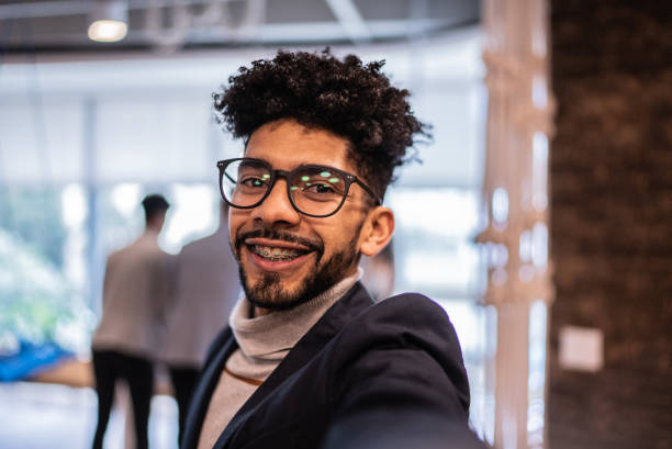 mid adult man taking selfie or filming at the office - camera point of view - filming point of view fotos imagens e fotografias de stock