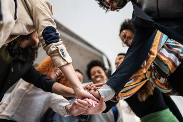 coworkers with stacked hands at the office - gemeenschap stockfoto's en -beelden