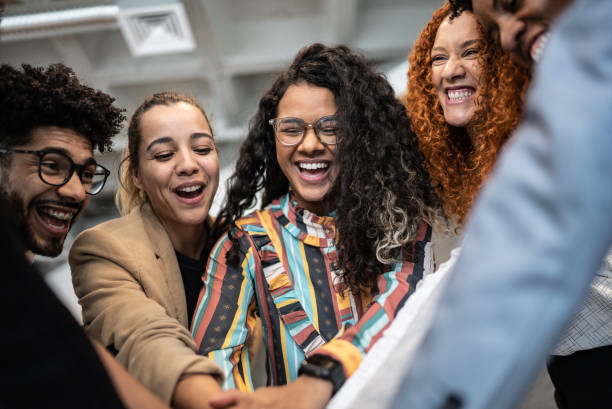 Coworkers with stacked hands at the office Coworkers with stacked hands at the office brazilian ethnicity stock pictures, royalty-free photos & images