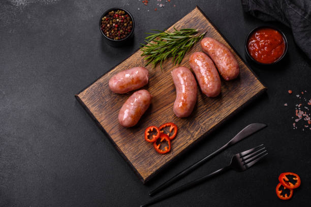 istock Grilled sausages with spices and herbs on a black background 1424987970