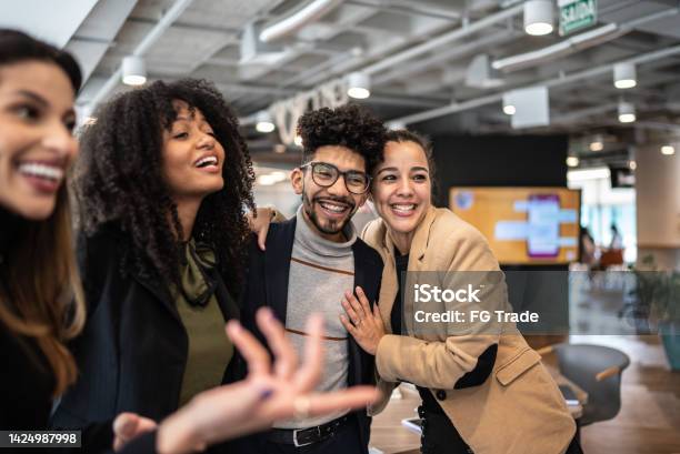 Coworkers Embracing And Talking At The Office Stock Photo - Download Image Now - Office, Working, Multiracial Group