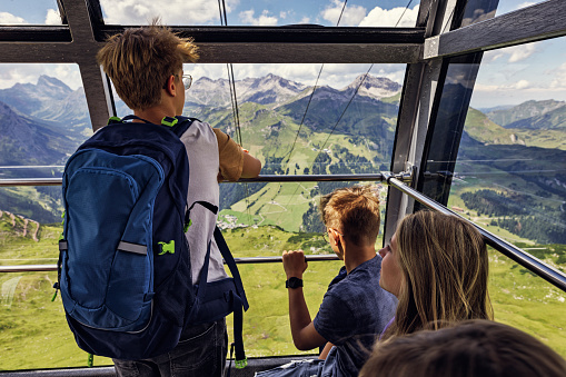 Family of hikers are using gondola lift cable cart ride to return from the mountains. They are looking at the views of European Alps.
Sunny summer day in Tyrol, Austria.
Canon R5