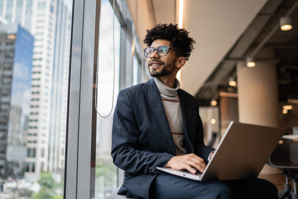 businessman contemplating in the office looking through the window - motivatie stockfoto's en -beelden