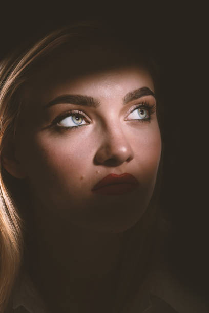 istock Beautiful woman portrait partly face covered with shadow 1424990280
