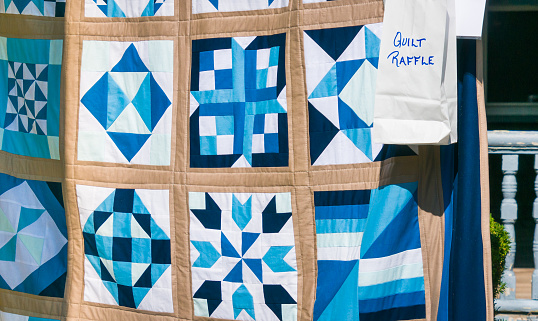 A handmade quilt of blues and whites on display during a church raffle on Cape Cod.