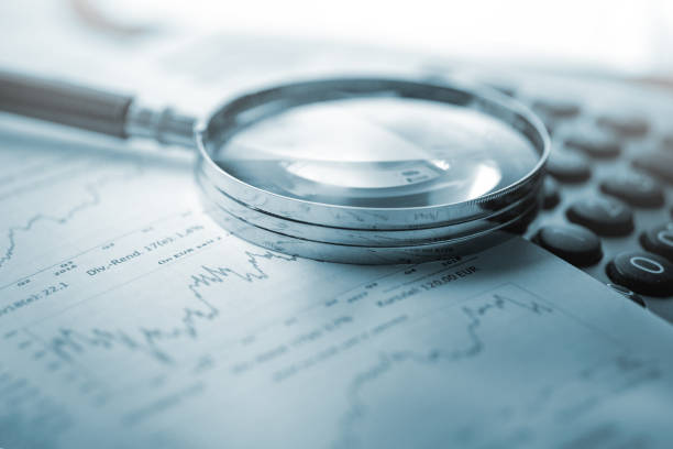 Magnifying glass, calculator and charts on paper stock photo
