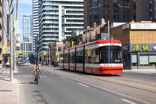 Toronto, Ontario - August 20, 2022 :  A 505 streetcar and cyclist moving along Dundas Street West approaching Chinatown.