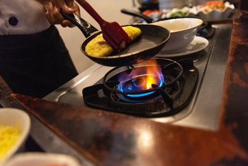 Chef preparing an omelette on open flame gas stove