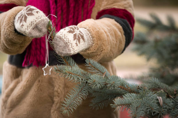 istock Young woman's hands decorating Christmas tree with crystal star decor outdoors. Traditional celebration. Winter, holidays season and Christmas concept. 1425014704