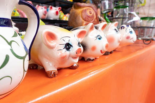 piggy bank made of traditional mexican talavera pottery, souvenir in a shop in mexico, repetitive pattern of many piggy banks for sale, saving money concept