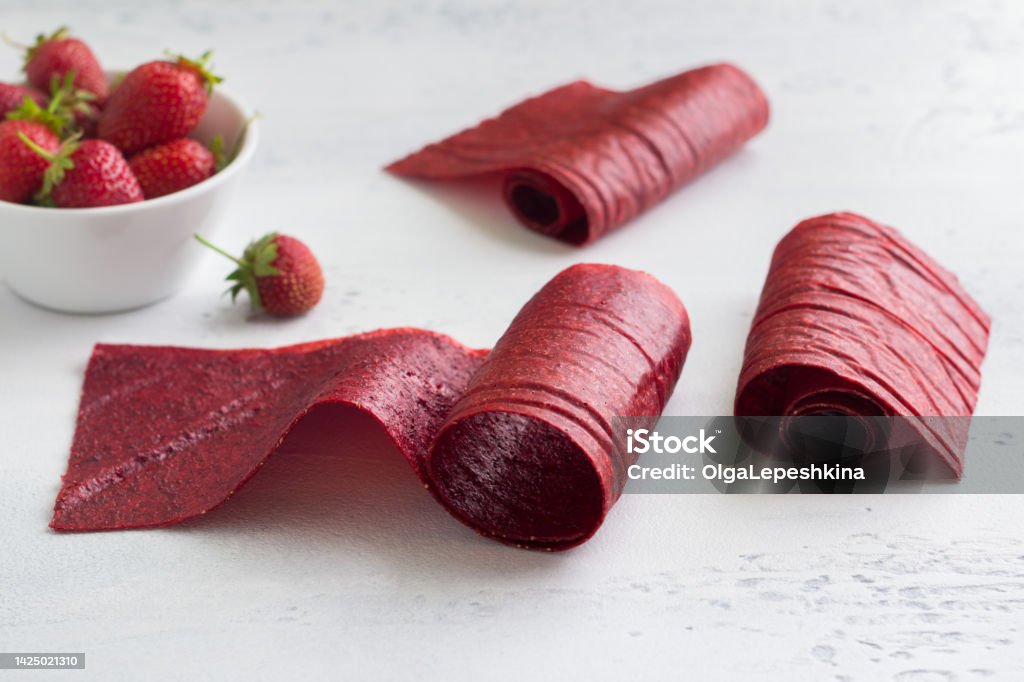 Homemade strawberry pastille with a bowl of fresh strawberries on a light blue background Backgrounds Stock Photo