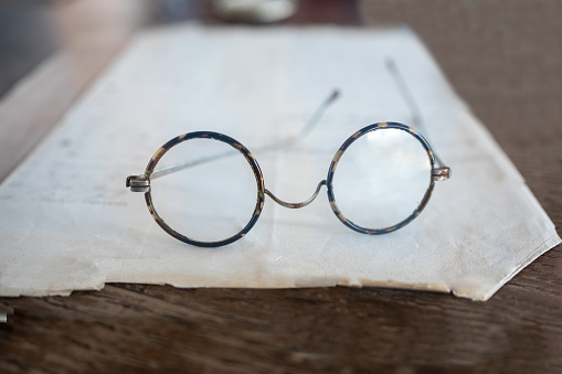 Close up old spectacles on a paper on a wooden desk