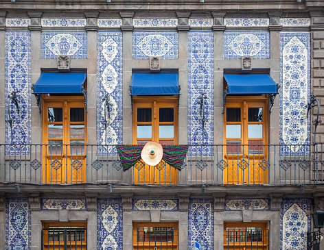 facade of colonial mexican house covered in blue talavera tiles, and a balcony with three doors, puebla city Mexico