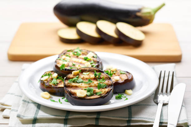 istock Salad with grilled eggplant, parsley and garlic on a white plate,selective focus.whole eggplant background. 1425036932