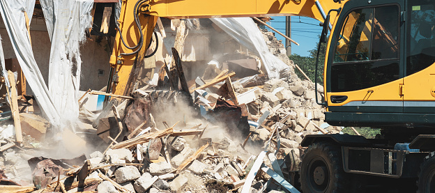 Demolition of building. Process of dismantling of house. Excavator breaks old building.