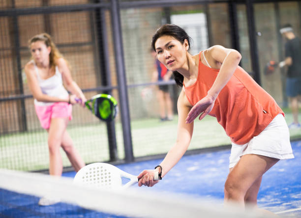 Sporty asian woman playing padel on indoor court Portrait of sporty adult asian woman playing padel on indoor court, ready to hit ball. Active lifestyle concept paddle ball stock pictures, royalty-free photos & images