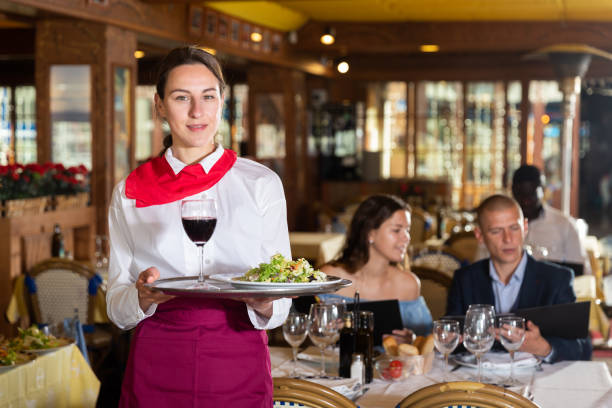 istock Waiter holding tray at restaurant with customers behind him 1425040390