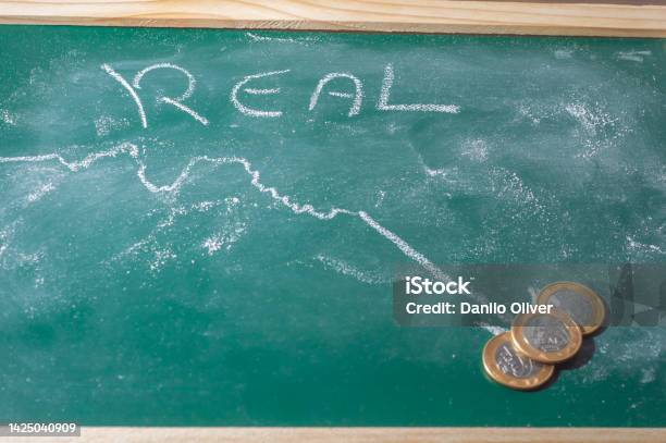 Green Chalkboard With The Word Real Written With White Chalk And A Graphics With A Plummeting Arrowcopy Space Stock Photo - Download Image Now