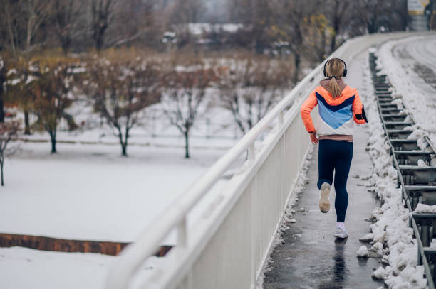 istock Rear backside view of female runner jogging on a bridge during winter 1425046913