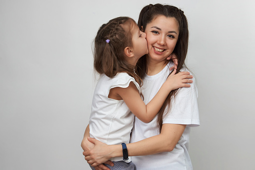 Happy woman and child girl 5-6 years old having fun. Young mother with little daughter portrait on white background with copy space. Mother's Day love family concept