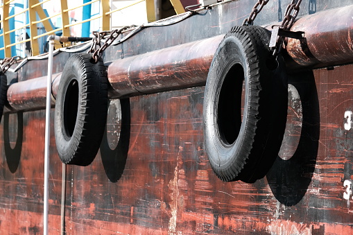 Banda Aceh, Indonesia - August 19, 2022 : two unused old rubber tires hanging on a ship