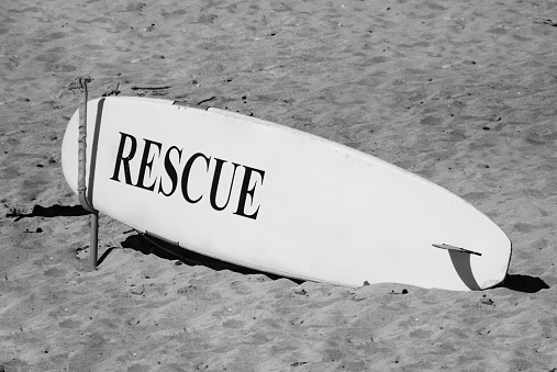 Close-up of a surfing board on the sand at the beach.  Black and white photography.