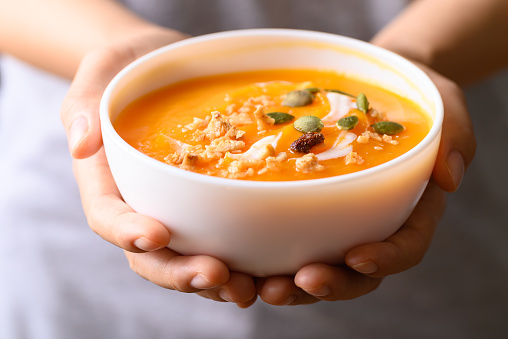 Butternut squash pumpkin soup in bowl holding by woman hand, Homemade food in autumn season