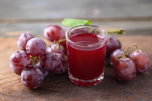 Red grape and juice in glass on wooden background, Healthy drink