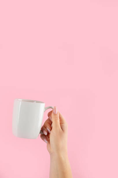 istock Arms raised up holding coffee cup on pink background. 1425087260