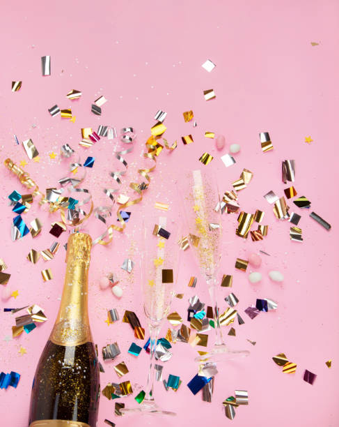 istock Champagne bottle with confetti on pink background. 1425087898