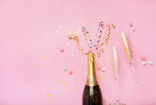 istock Champagne bottle with confetti on pink background. 1425088354