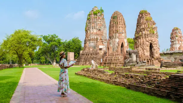 Ayutthaya, Thailand at Wat Mahathat, women with a hat and tourist maps visiting Ayyuthaya Thailand. Tourist with map in Thailand