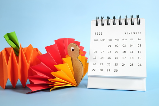 Hello November 2022 with Thanksgiving Day concept. Desk calendar with turkey and  pumpkin paper craft on blue background.
