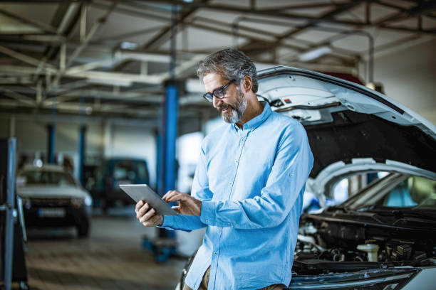 inspector feliz usando tableta digital en el taller de reparación de automóviles. - auto repair shop mechanic digital tablet customer fotografías e imágenes de stock