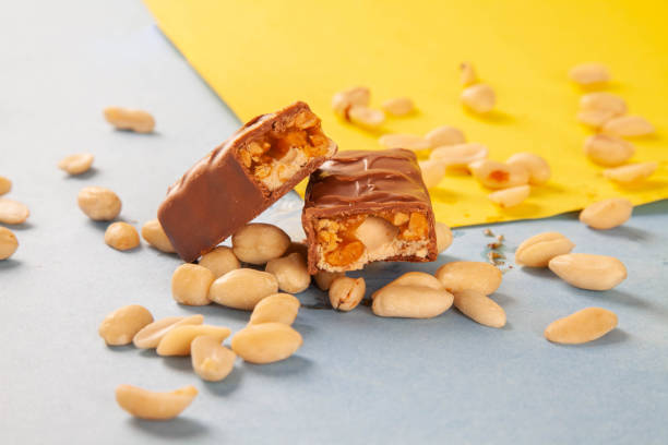 Chocolate bar with nuts and caramel layering inside with peanuts all around.