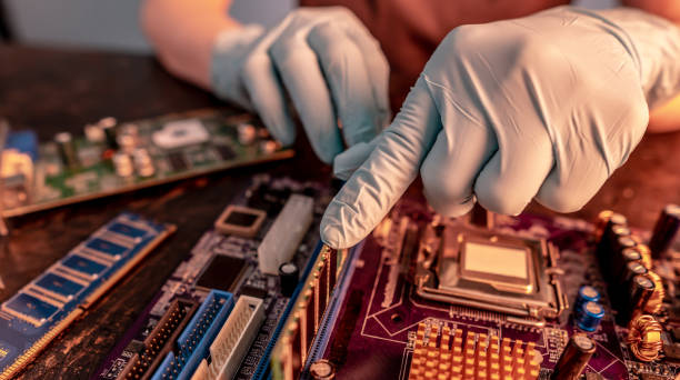 The engineer's gloved hand holds the computer's RAM chip against the background of the motherboard stock photo