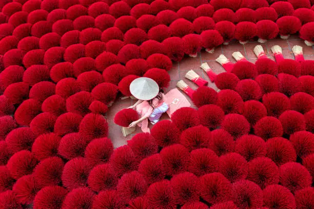 Asian woman wearing ao dai dress with Incense sticks drying outdoor in Hanoi, Vietnam.