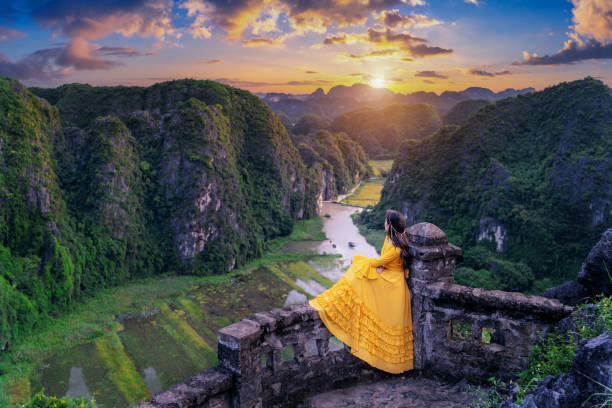 Woman tourist sitting on Hang Mua viewpoint. Popular tourist attraction at Tam Coc, Ninh Binh. Vietnam. Woman tourist sitting on Hang Mua viewpoint. Popular tourist attraction at Tam Coc, Ninh Binh. Vietnam. tam o'shanter stock pictures, royalty-free photos & images