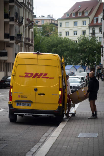 通りに停められた黄色いdhl配送トラックの正面図 - driving delivery van global business dhl ストックフォトと画像