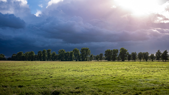 View of a pasture under a cloudy sky with rain clouds on an autumn day. Fantastic, dreamy, mystical.