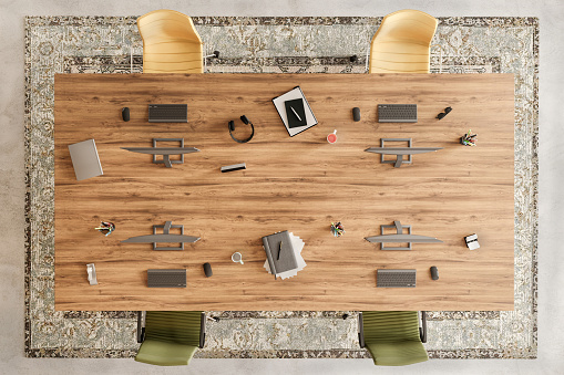 Modern office space interior with large wooden desk. Chairs, computers, headphones, notebooks, decorative carpet, concrete floor. Template for copy space. Render.