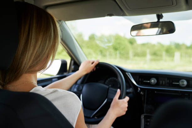 Rear view of caucasian blonde woman driving a car stock photo