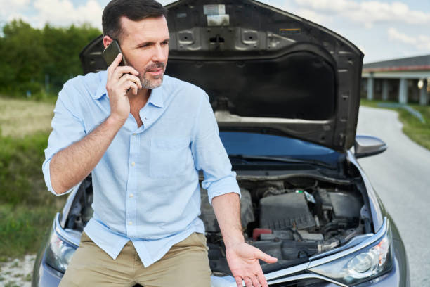 istock Caucasian man talking by mobile phone with broken car 1425105601