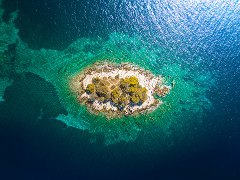 Aerial view of a small uninhabited island in the mediterrean sea close to the shore of Croatia.