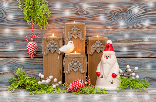 Advent candles and Santa Claus are decorated with fir branches. Four Christmas candlesticks on a wooden table. The concept of Christmas and New Year. Blue background.