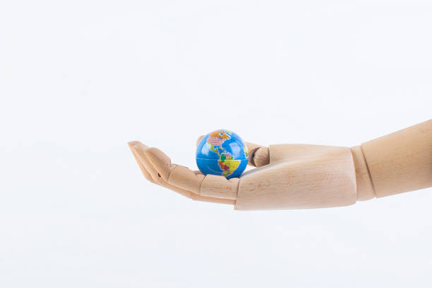 Wooden dummy hand holding an earth globe