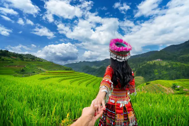 Hmong ethnic minority holding man's hand and leading him to rice terraces in Mu Cang Chai, Yen Bai, Vietnam.