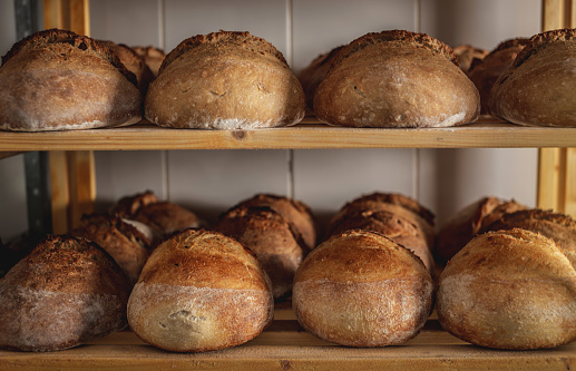 Freshly baked round wheat bread with a golden crispy crust on sourdough lies on the shelves in the bakery.