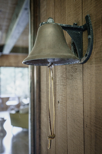 Brass bell hanging on wall at entrance of home