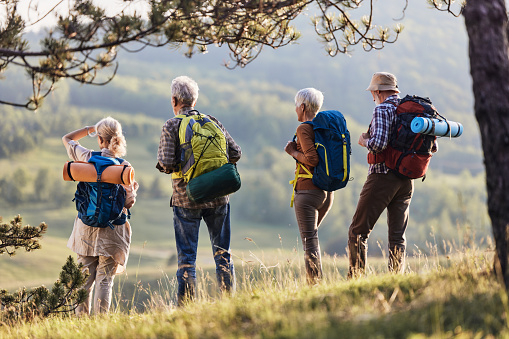 Back view of mature friends looking at view while spending a spring day on hiking in nature.